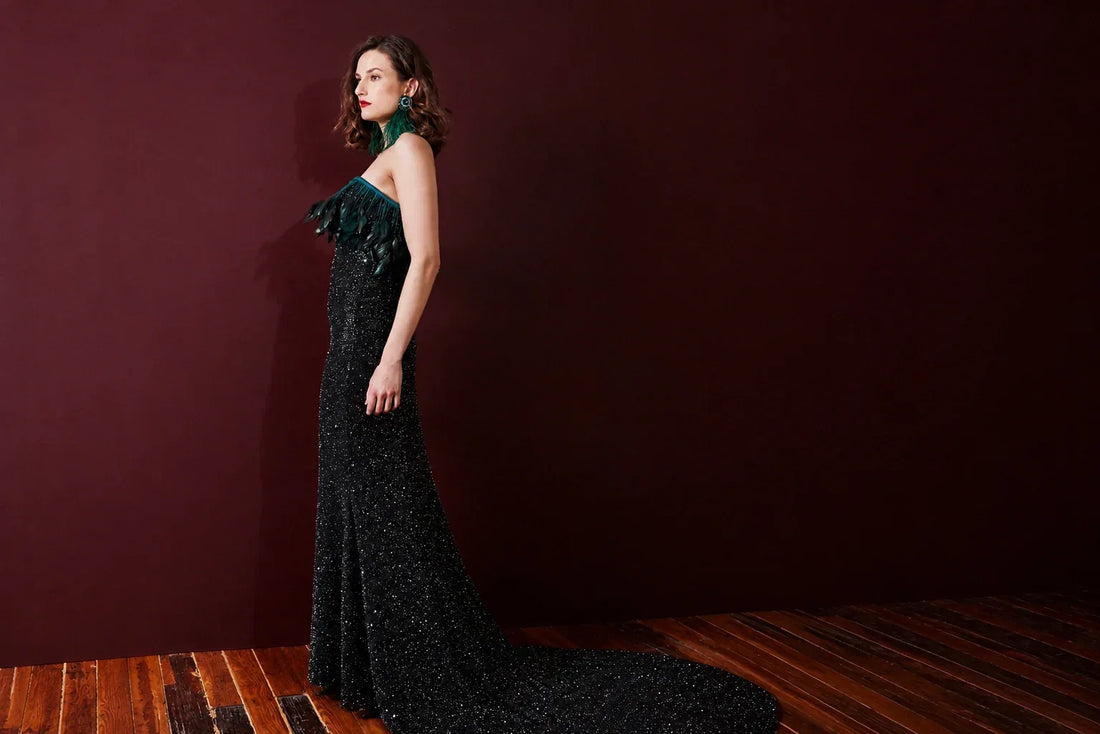 Woman wearing a black floor-length evening gown with emerald feather detailing for a black-tie gala