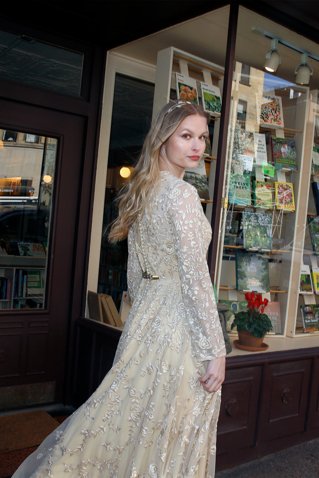 Side and back view of Olympia by Lavanya Coodly, showing intricate silk-thread embroidery on pale gold tulle, sheer long sleeves, and a flowing evening gown skirt.